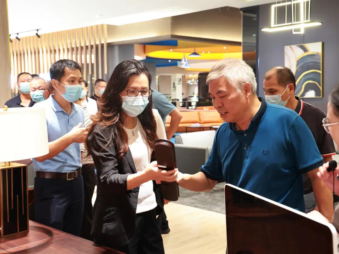 迪歐家具集團董事副總裁黃云林為調(diào)研組展示實木辦公家具產(chǎn)品